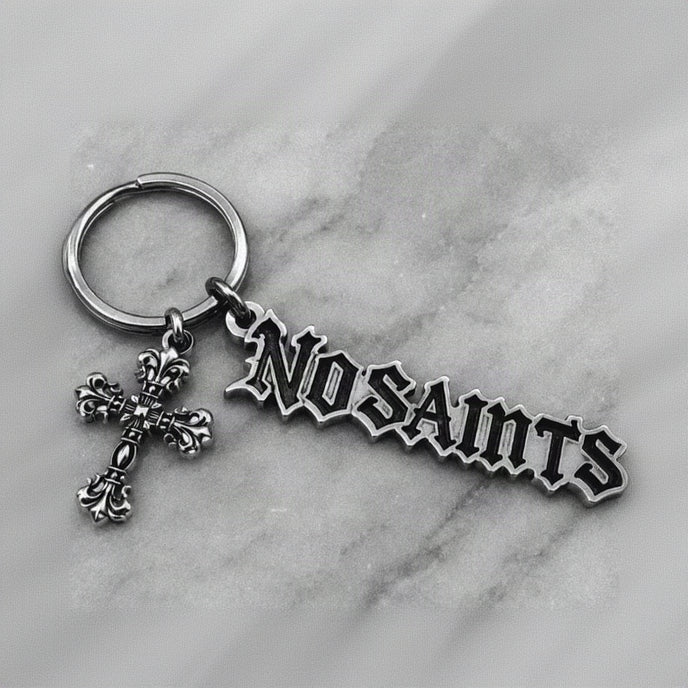 NOSAINTS Logo Keychain with cross charm on marble surface
